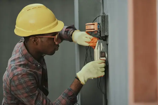 A technician working at an open electrical cabinet.